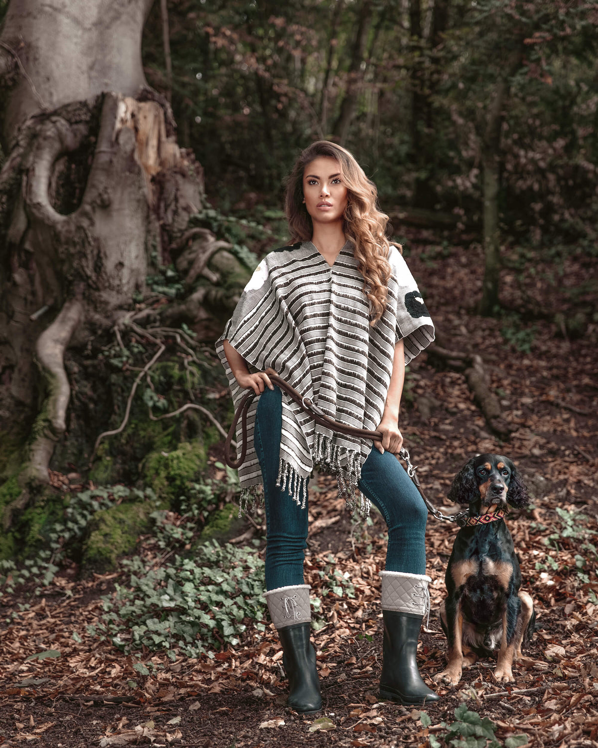 Relaxed woman standing in the forest walking with her dog wearing Táabal Flowers Poncho by 32 Estados