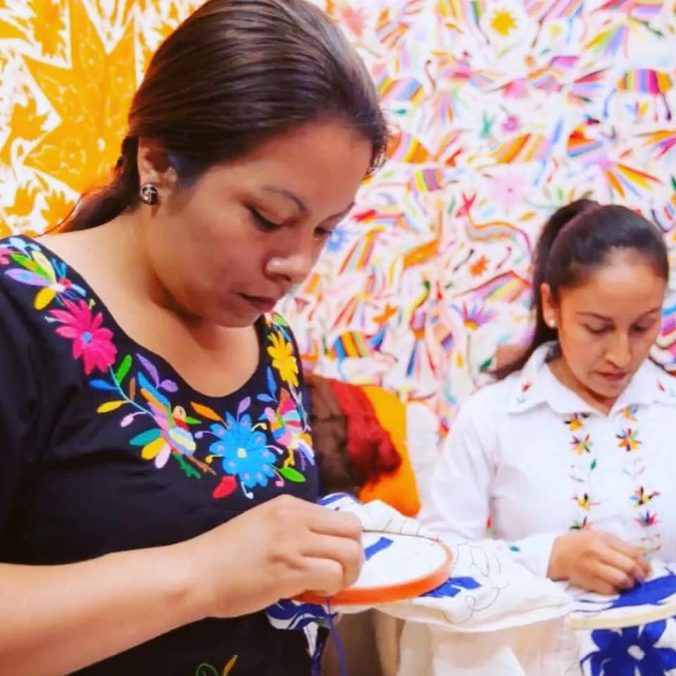 Artisans working on the embroidery of the bags