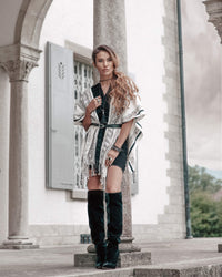 Confident woman leaning on a pillar wearing Táabal Black & White poncho for going out